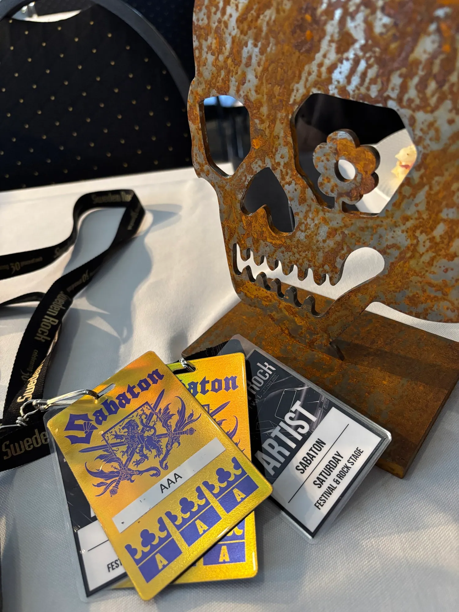 A rusted metal skull prop with event badges on a table