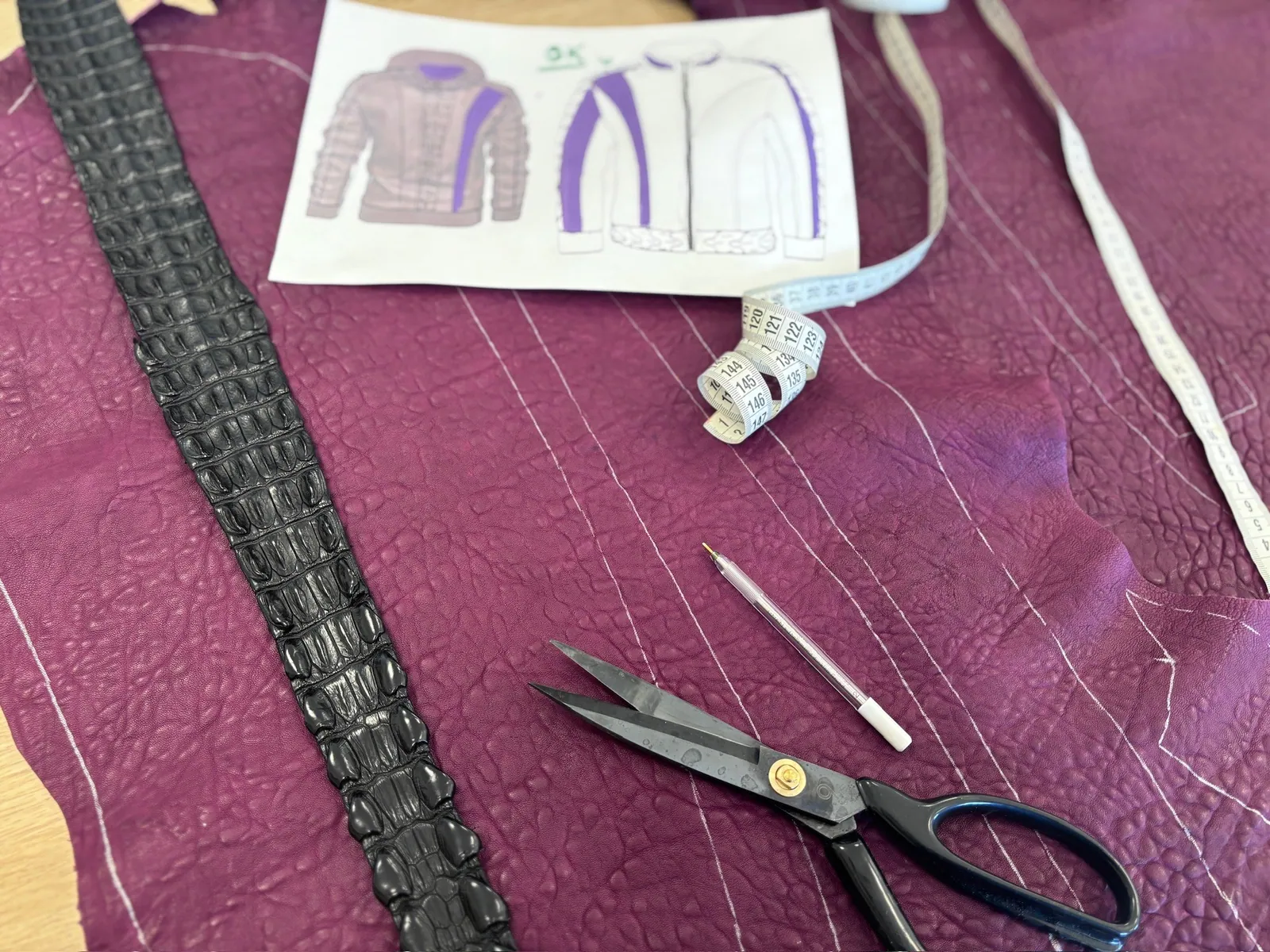 Leather pieces, a paper pattern and scissors laid out on a table