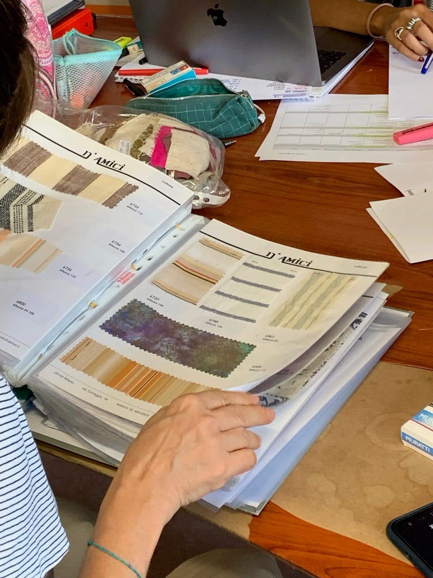 Hands sorting fabric swatches and printed design documents