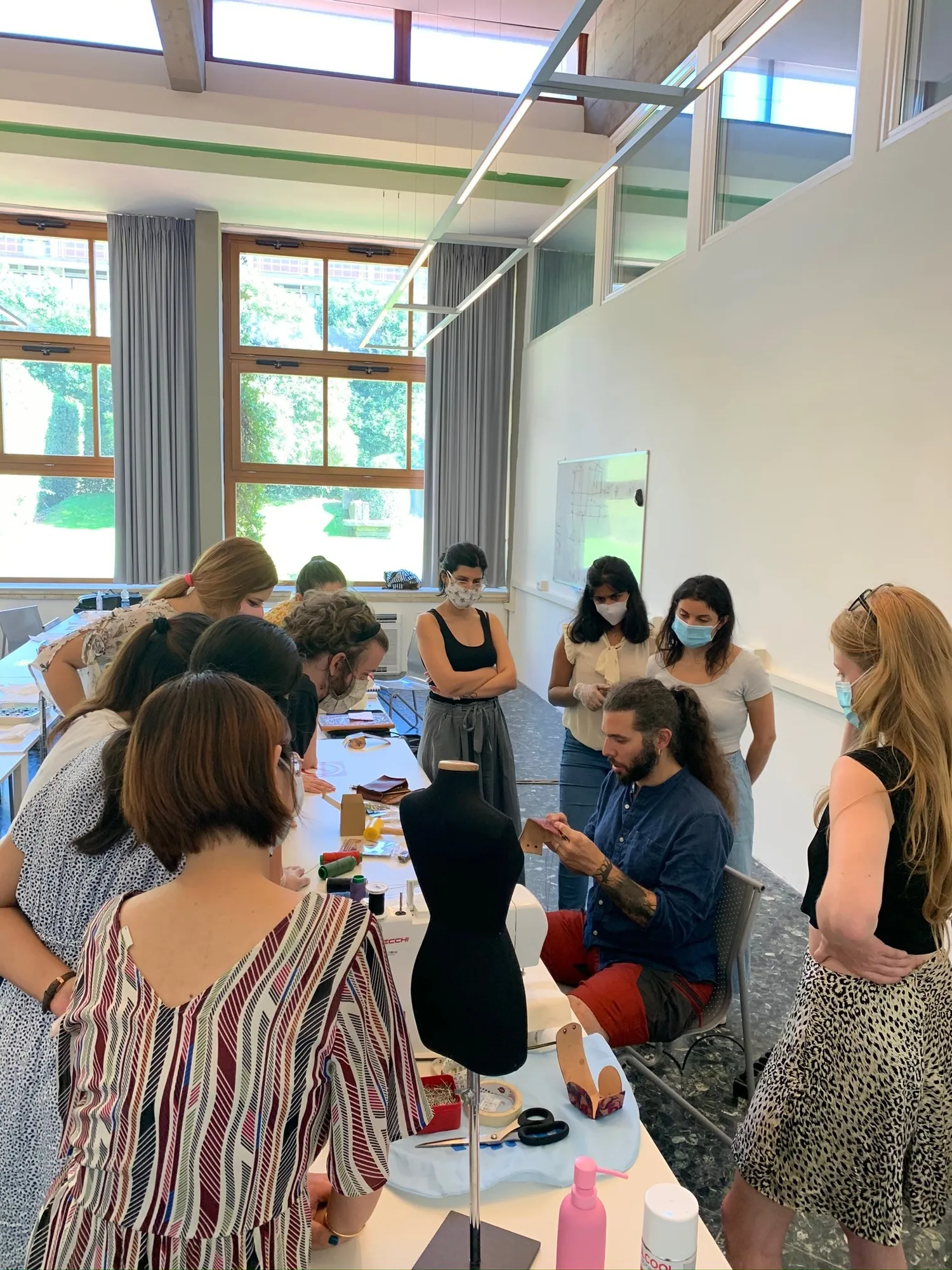 Workshop participants gathered around a mannequin in a bright hall