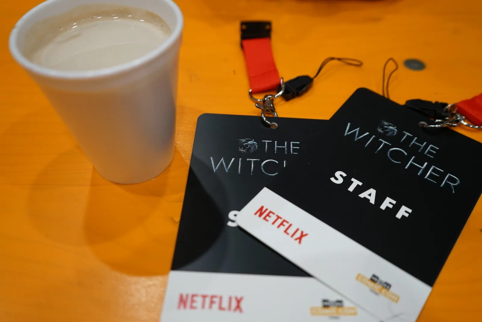 Netflix The Witcher staff badges and a coffee cup on an orange table