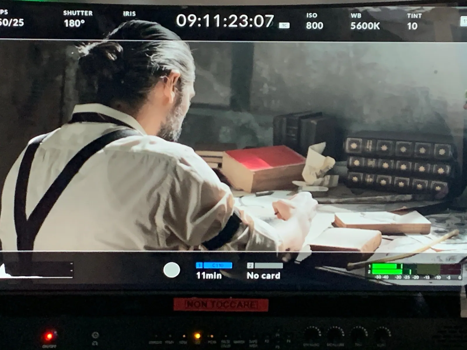 A man in suspenders at a monitor on a production set