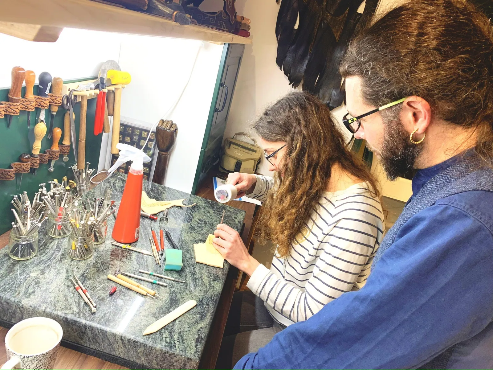 Two people working at a leather tool bench during a workshop